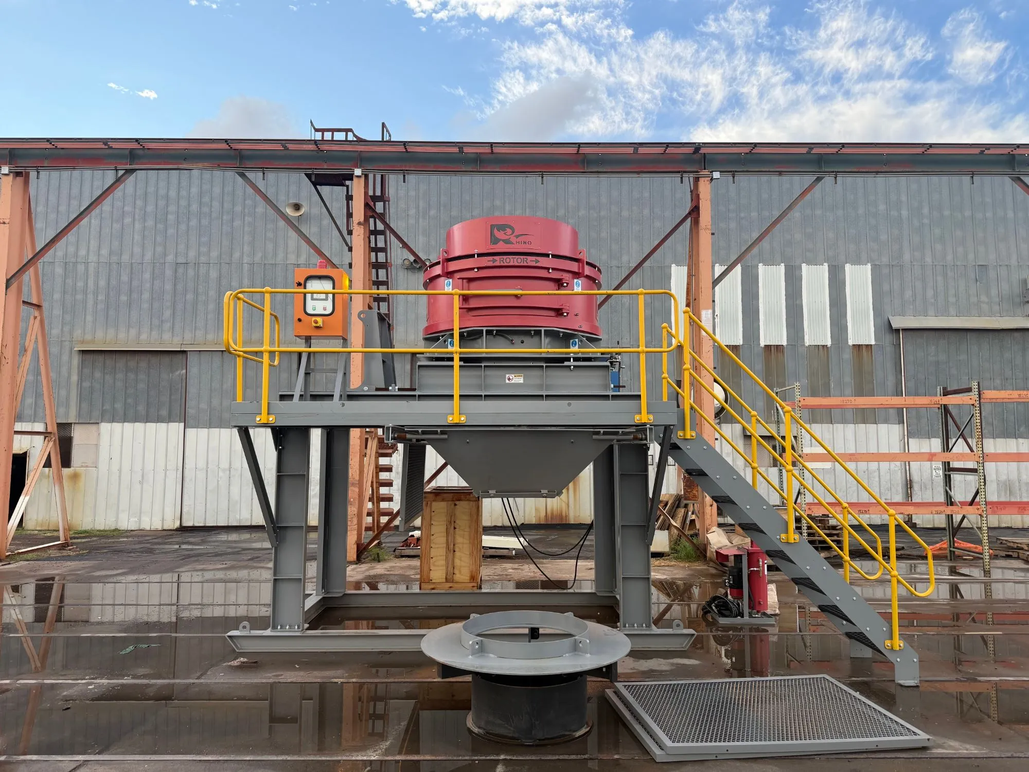 Red Rhino VSI crusher installed on an elevated platform with yellow safety railings and access stairs